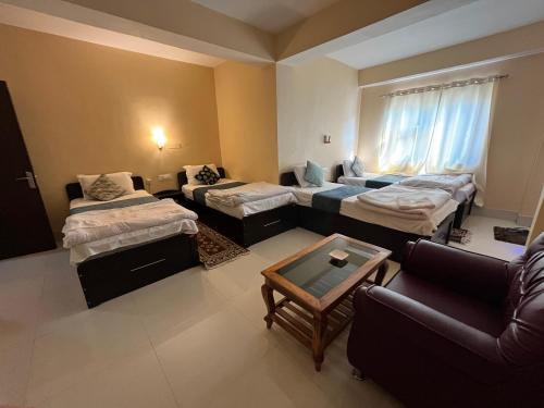 a room with three beds and a couch at Hotel Cymbidium Residency in Tādong