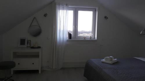 a white bedroom with a bed and a window at Widokówka in Tarnobrzeg