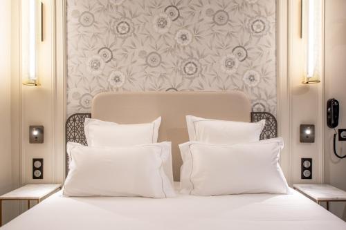 a white bed with white pillows and a floral wallpaper at ELSA, Hôtel Paris by Collection Vesper in Paris