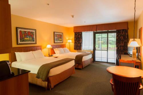 a hotel room with two beds and a table at Hôtel St-Bernard in St-Bernard de Lacolle