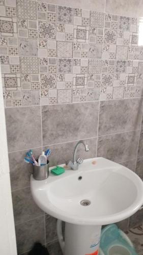 a white sink in a bathroom with a tile wall at Najib in Djerba