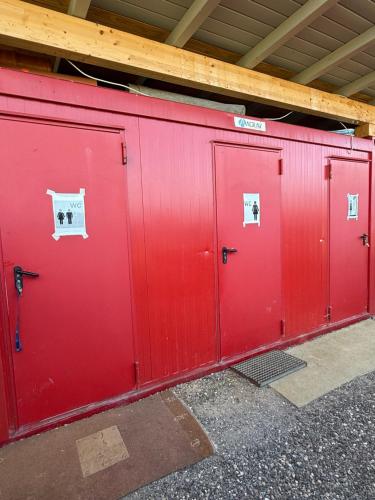 a row of red doors with signs on them at Camping Dorfer in Spielberg