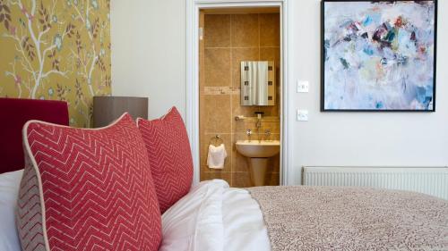 a bedroom with a bed with red pillows and a sink at Sea Spray Hotel in Brighton & Hove