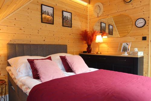 a bedroom with a bed in a room with wooden walls at Mazury Czerwony Domek Jacuzzi in Romany