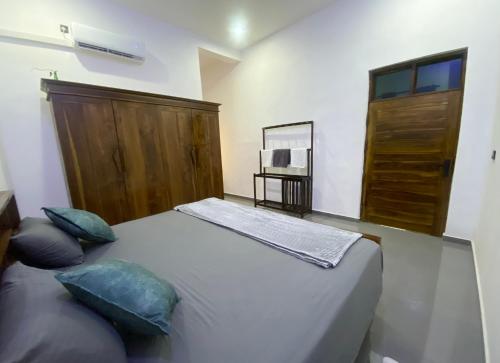 a bedroom with a bed with two pillows and a wooden door at ZEN House Arugambay in Arugam Bay