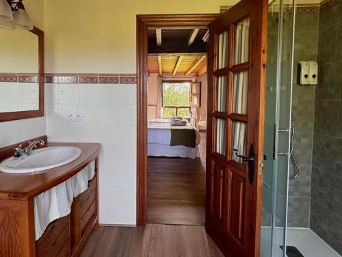 a bathroom with a sink and a shower and a bed at El Balcón Del Profesor in Cereceda