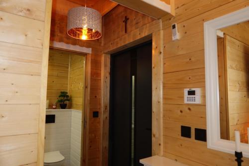 a bathroom with wooden walls and a black door at Mazury Czerwony Domek Jacuzzi in Romany
