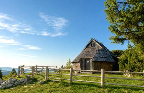 an old barn in a field next to a fence at Chalet Velika Planina with Sauna - I FEEL ALPS in Stahovica