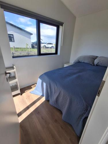 a bedroom with a bed and a large window at Hólmahjáleiga Guesthouse in Hvolsvöllur