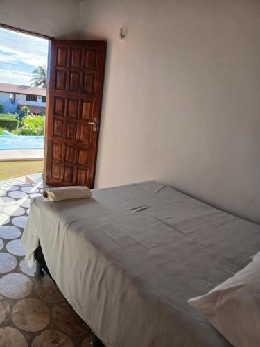 a bedroom with a bed with a door and a window at Pousada Praiamar in Beberibe