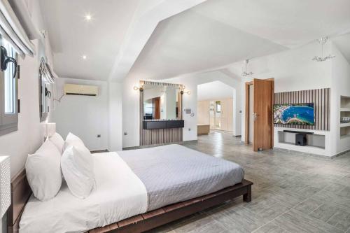 a bedroom with a large white bed with white pillows at Villa Elegio in Kavos