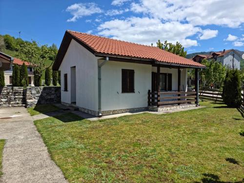 a small white house with a grass yard at Apartmani LUX in Kolašin