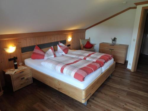 a bedroom with a large bed with red and white pillows at Gästehaus Koros in Fischen