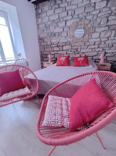a bedroom with a bed and a chair with red pillows at OLOO Habitat - Le 3 in Lure