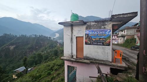 a building with a sign on the side of a mountain at Dakshu guest house in Ukhimath