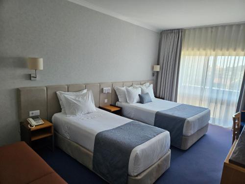 a hotel room with two beds and a couch at Hotel Feira Pedra Bela in Santa Maria Da Feira