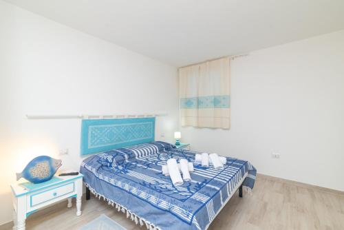 a white bedroom with a blue bed and a blue chair at Bilocale nuovo Budoni centro in Budoni