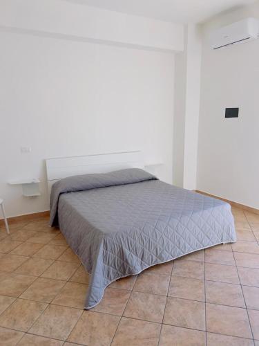 a bed in a white bedroom with a tiled floor at Corso Messina in Crotone