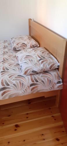 an unmade bed with white sheets on a wooden floor at Sušica Apartman in Kovačka Dolina