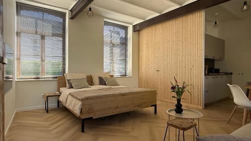 a bedroom with a bed and a table and some windows at B&B Sjaanderhof in Maastricht
