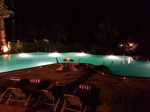 a swimming pool at night with chairs and a table at The Solluna Resort in Garjia