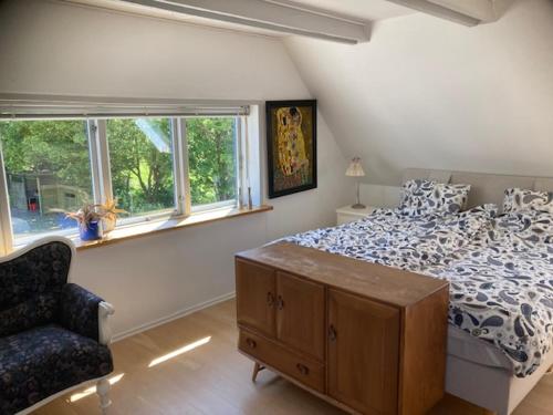 a bedroom with a bed and a chair and a window at Main House - Rolsø Retreat in Knebel
