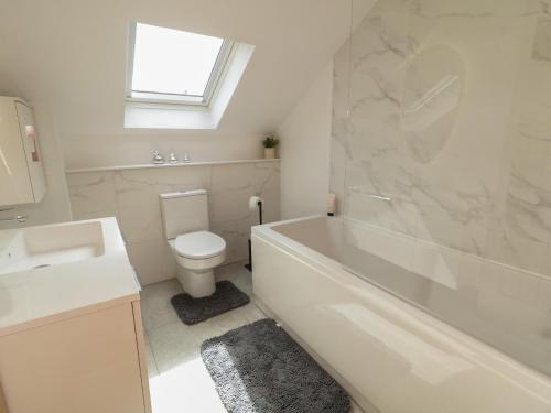 a bathroom with a tub and a toilet and a sink at Brook Cottage in Coleraine