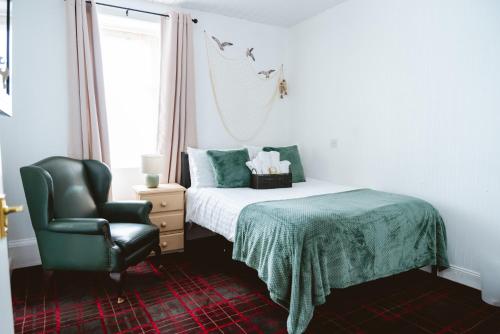 a bedroom with a bed and a chair at Ocean Breeze Inn in Eyemouth