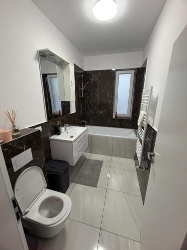 a bathroom with a toilet and a sink and a tub at C&A Apartment in Giroc