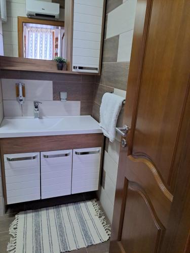 a bathroom with a sink and a mirror and a door at Apartmani Sorić in Prijeboj