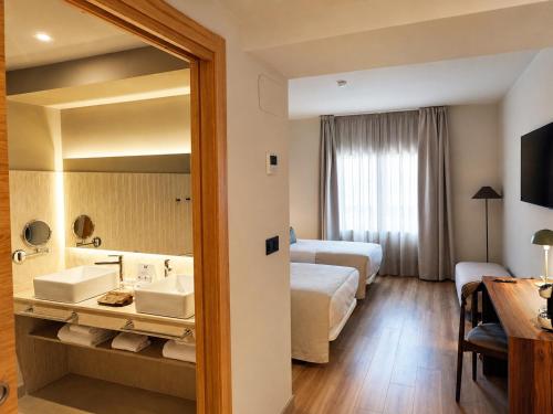 a hotel room with two beds and a mirror at Hotel La Palloza in Lugo