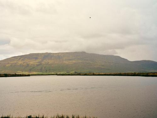 a mountain in front of a large body of water at Kjarnholt in Kjarnholt