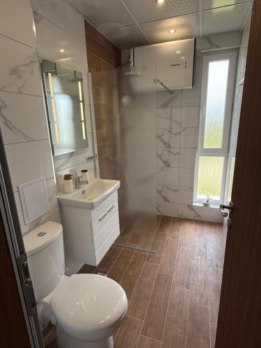 a white bathroom with a toilet and a sink at Къща Грийн Хаус in Chernomorets