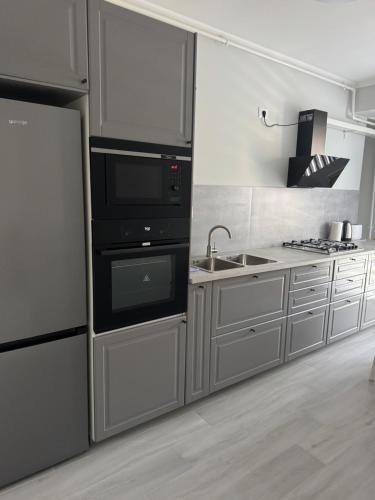 a kitchen with a stove and a sink and a refrigerator at Modern Apartment Constanța in Constanţa