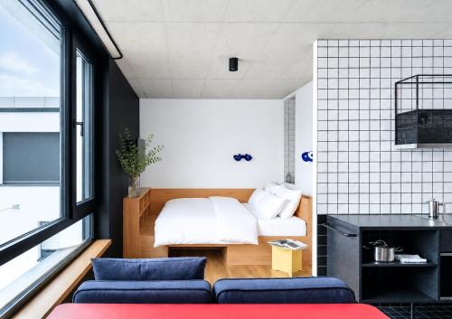 a bedroom with a bed and a couch in a room at STAYERY Cologne Ehrenfeld - Live Music Hall in Cologne
