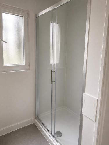 a glass shower in a bathroom with a window at Snowdon Apartments in Stirling