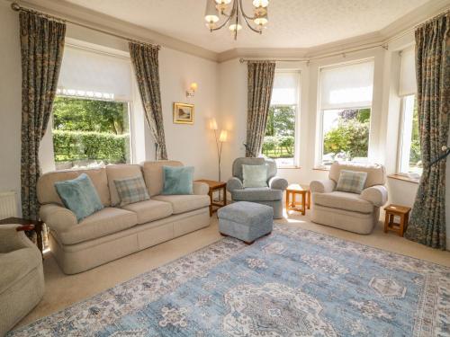 a living room with couches and chairs and windows at Riverdene in Omagh