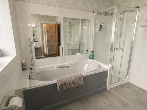 a white bathroom with a tub and a shower at Riverdene in Omagh