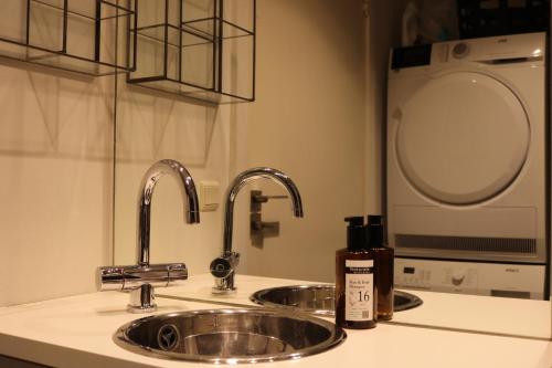 a kitchen sink with two faucets and a mirror at Aurora Studio Apartments in Nuuk