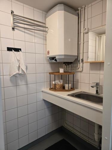 a white tiled bathroom with a sink and a mirror at Kyyveden Kartano Horsma 14 in Mikkeli