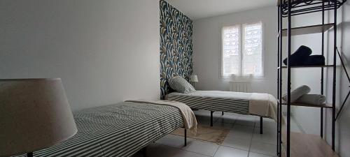 a white room with two beds and a window at Berges de la Suippe in Warmeriville