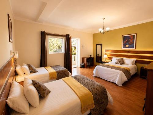 a hotel room with three beds and a window at Casa de Avila Hotel in Arequipa