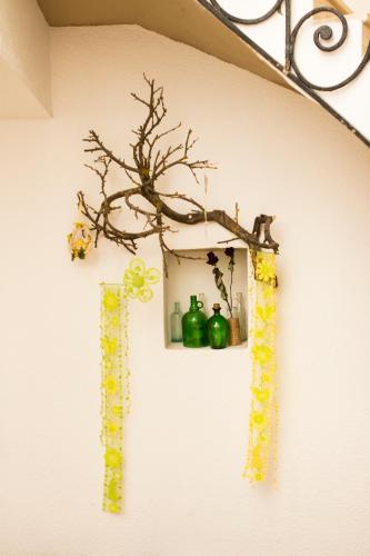 a wall with a shelf with green bottles and a branch at Borbarátok Háza in Győr