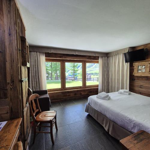 a bedroom with a bed and a chair and a window at M4478 Mollino Rooms in Breuil-Cervinia