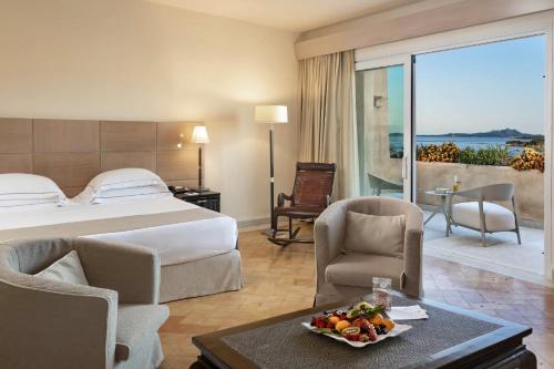 a hotel room with a bed and a table with a bowl of fruit at L'Ea Bianca Luxury Resort in Baja Sardinia