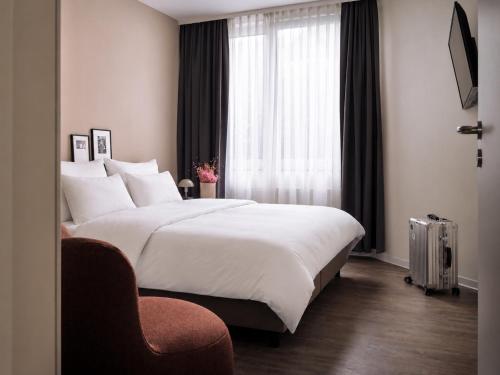 a bedroom with a large white bed and a window at STAYERY Cologne Sülz - Uni-Center in Cologne