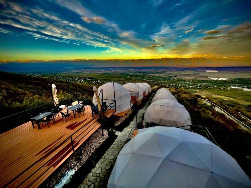 a group of domes with tables and chairs on a deck at Signagi Glamping in Sighnaghi