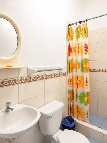 a bathroom with a toilet and a sink and a shower curtain at Hospedaje Triton in Máncora