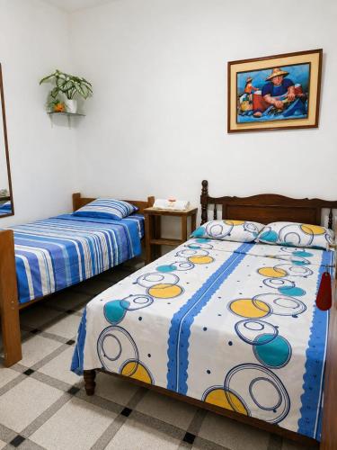 a bedroom with two beds and a painting on the wall at Hospedaje Triton in Máncora