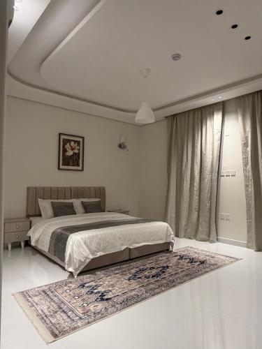 a bedroom with a bed and a rug on the floor at شقق واحة المحمدية in Baljurashi